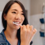 woman brushing her teeth as part of a daily dental routine